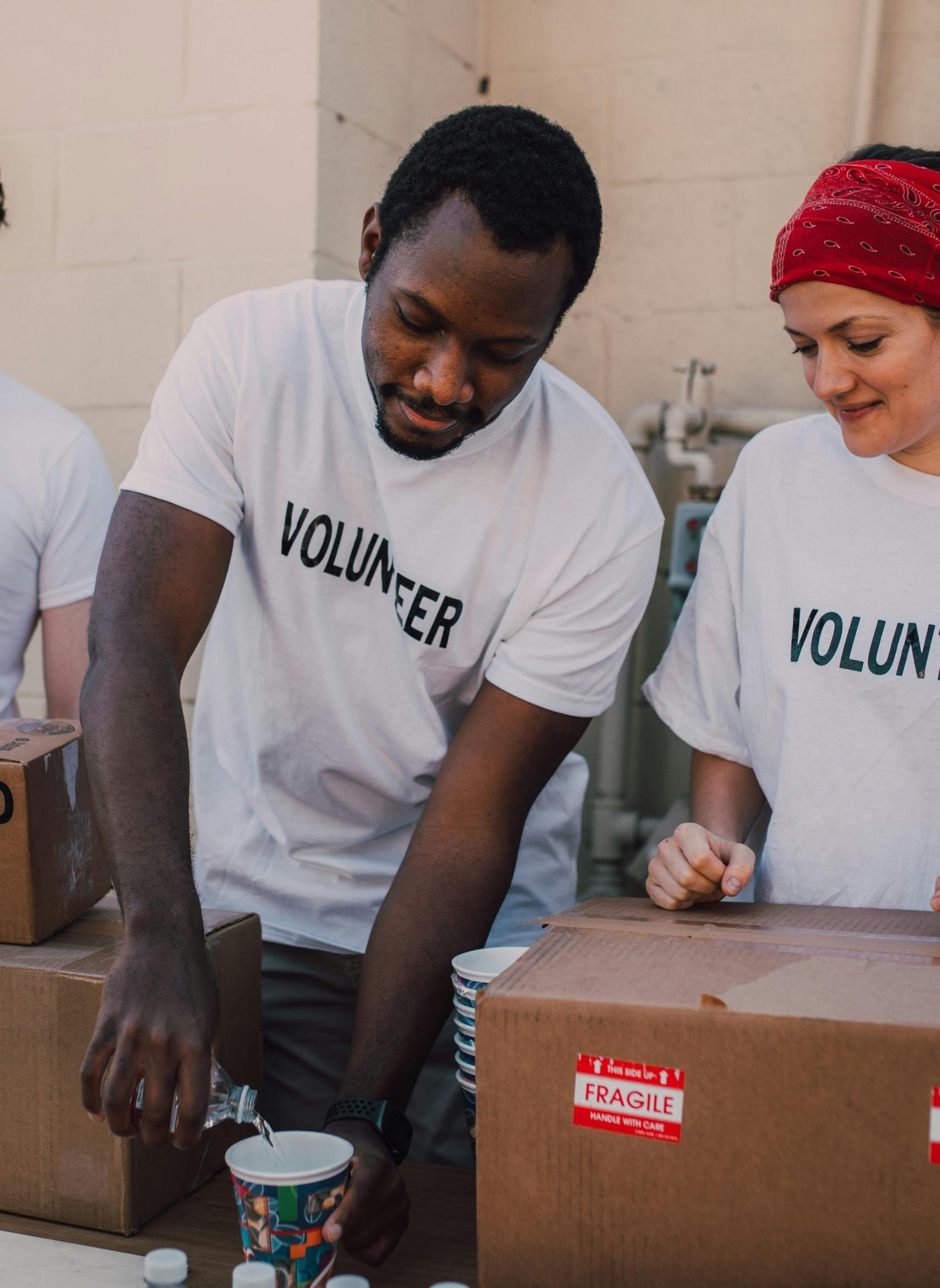 A group of volunteers working together, pouring beverages into cups outdoors.